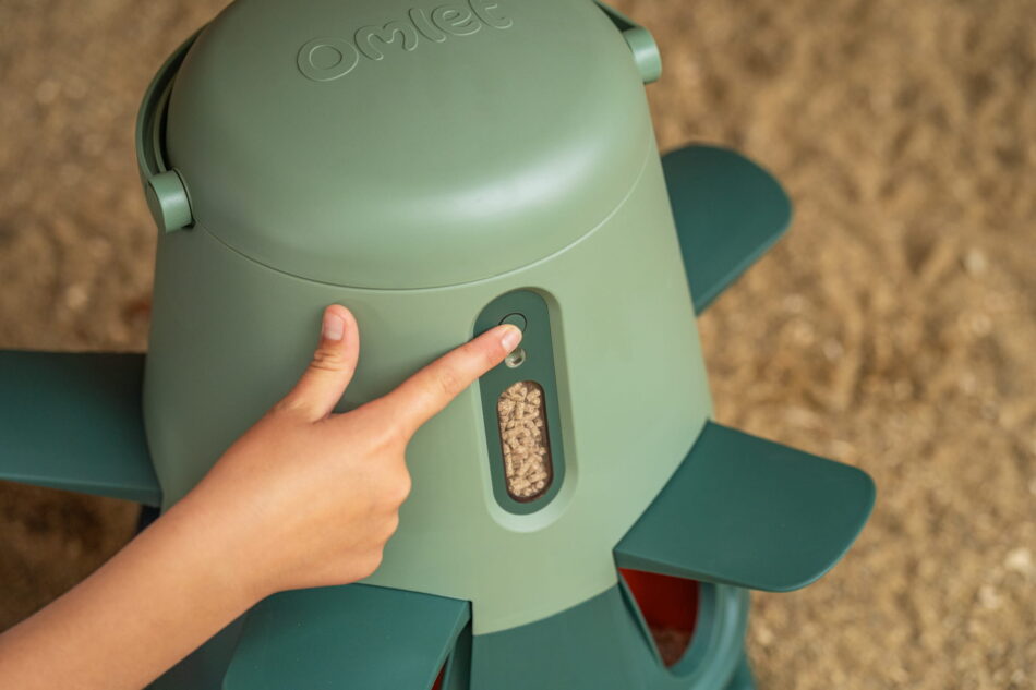 pige, der trykker på knappen på omlets smarte foderautomat